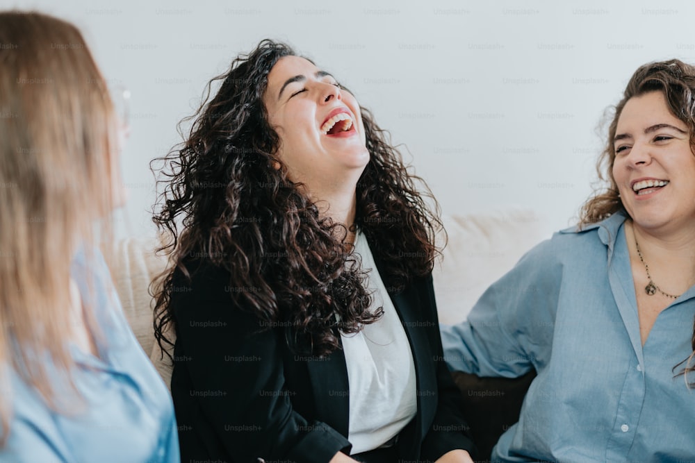 Zwei Frauen lachen, während sie auf einer Couch sitzen