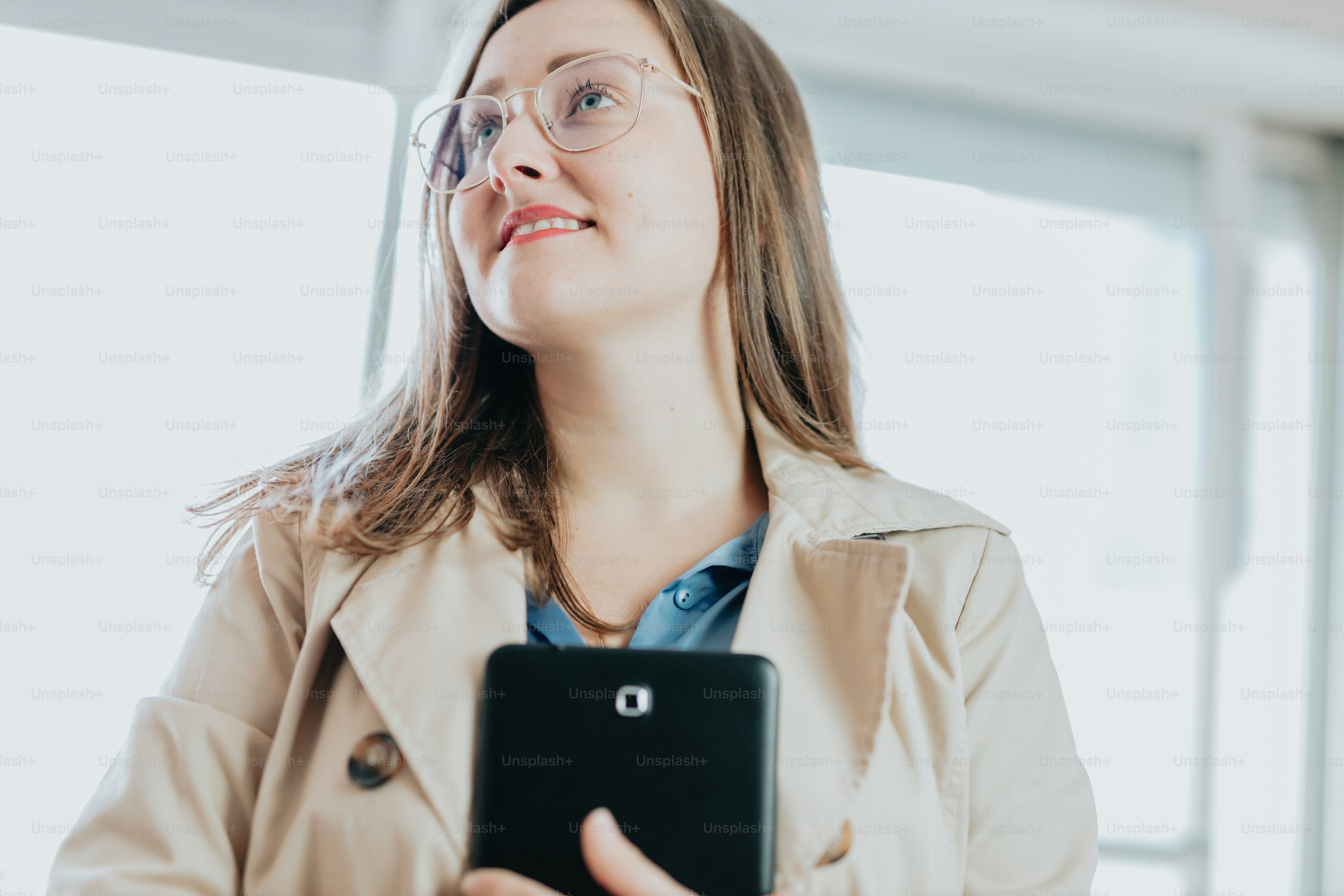 uma mulher em um trench coat segurando um comprimido