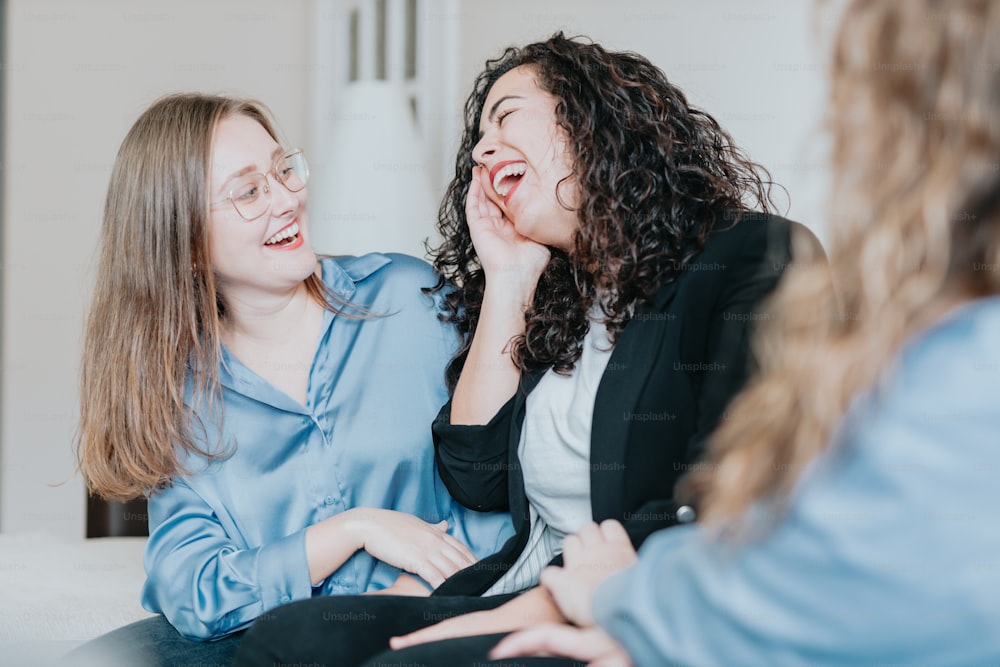 two women laughing while sitting on a couch