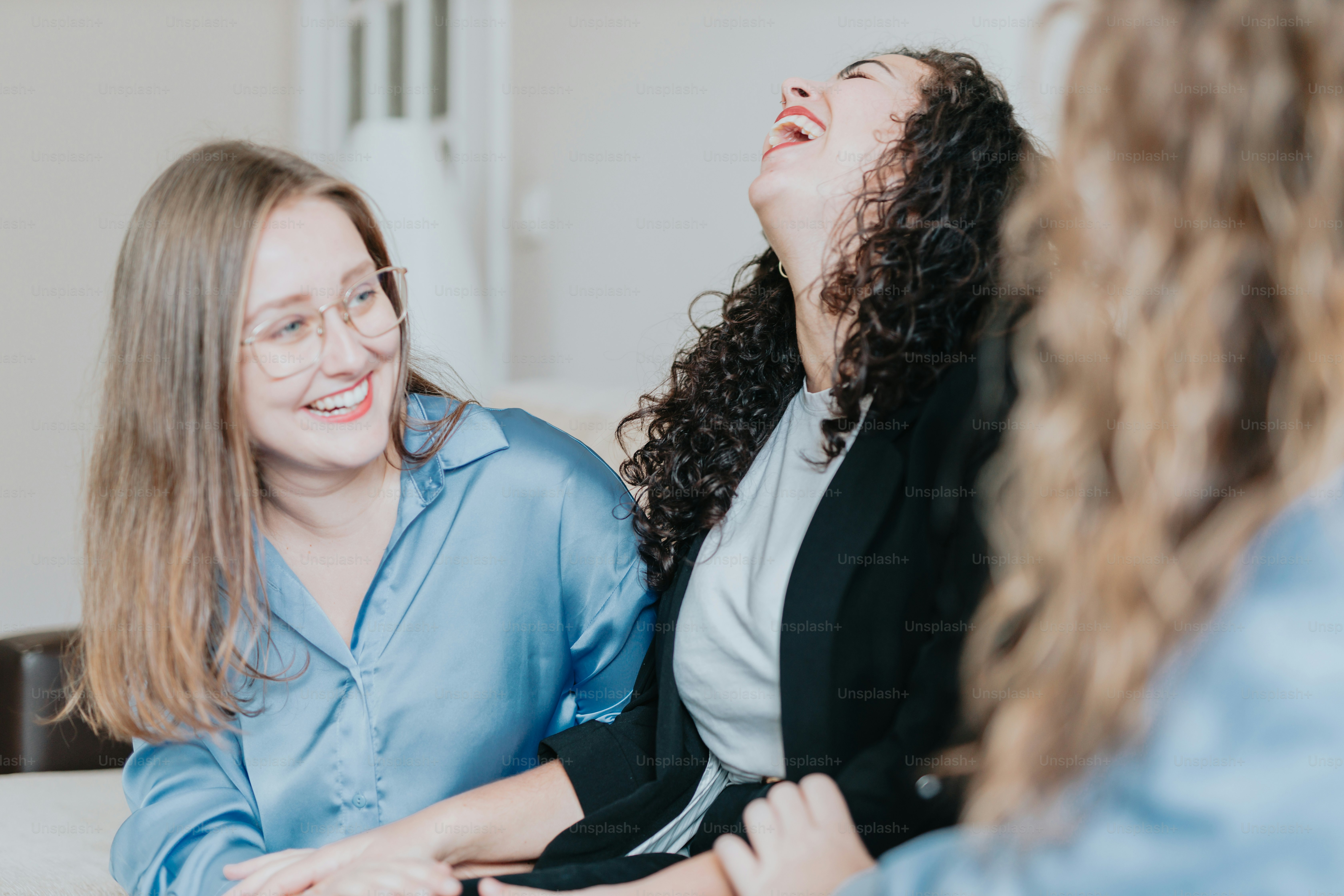 duas mulheres rindo enquanto sentadas em um sofá
