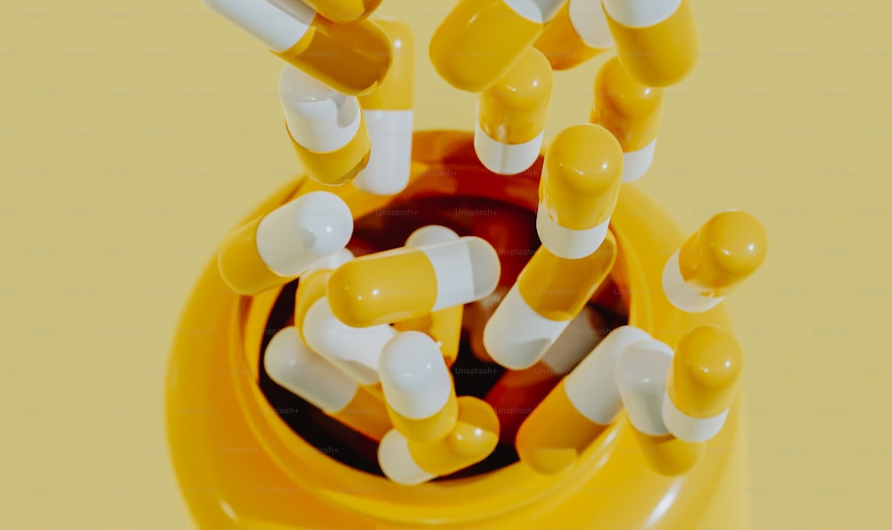 un groupe de pilules jaunes et blanches dans un récipient jaune