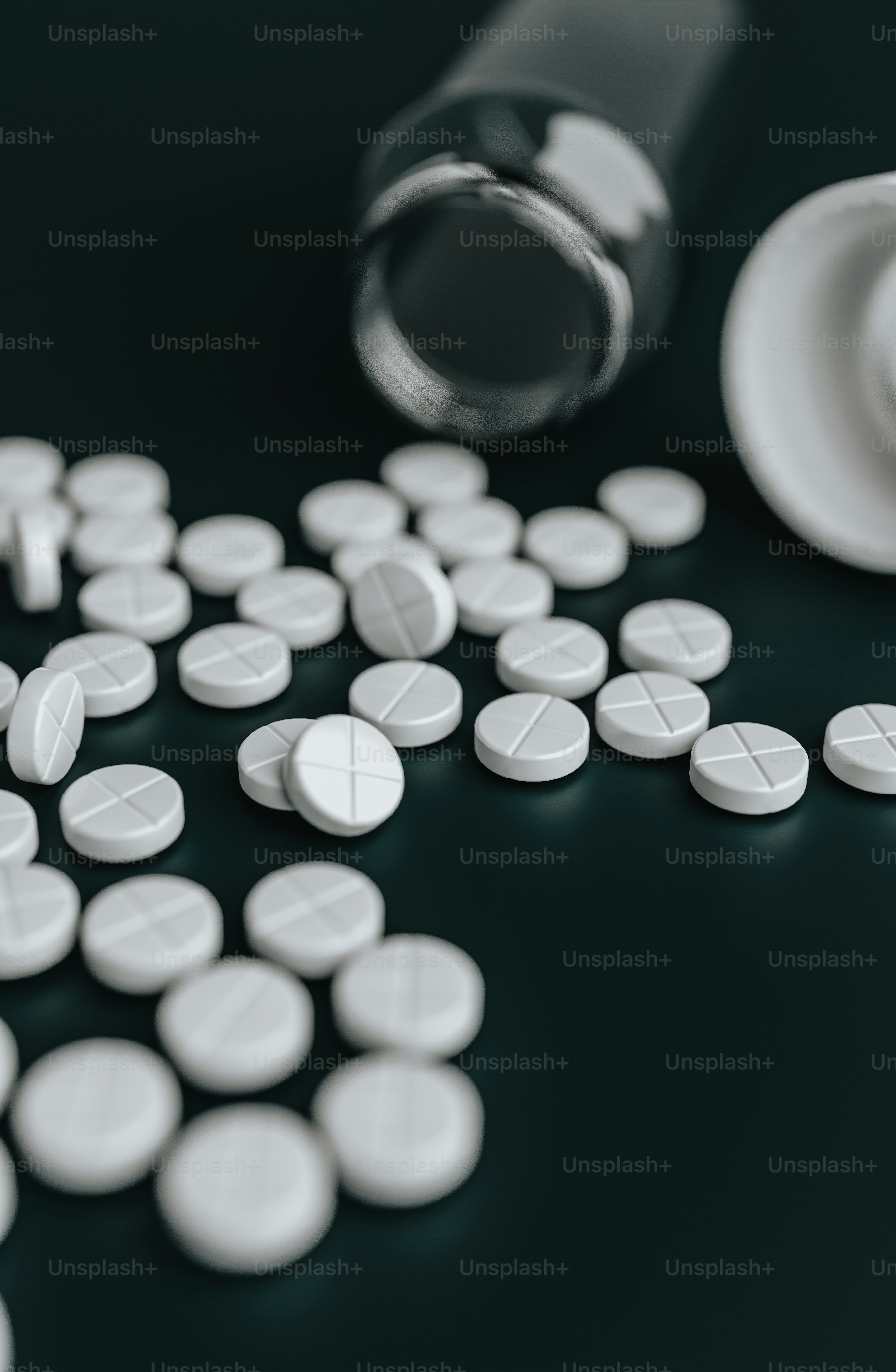 white pills spilling out of a bottle onto a black surface