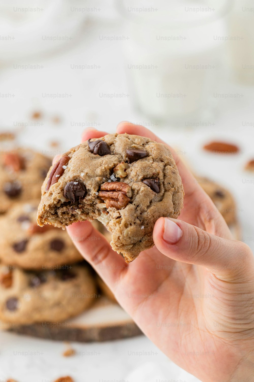 a person holding a chocolate chip cookie in their hand