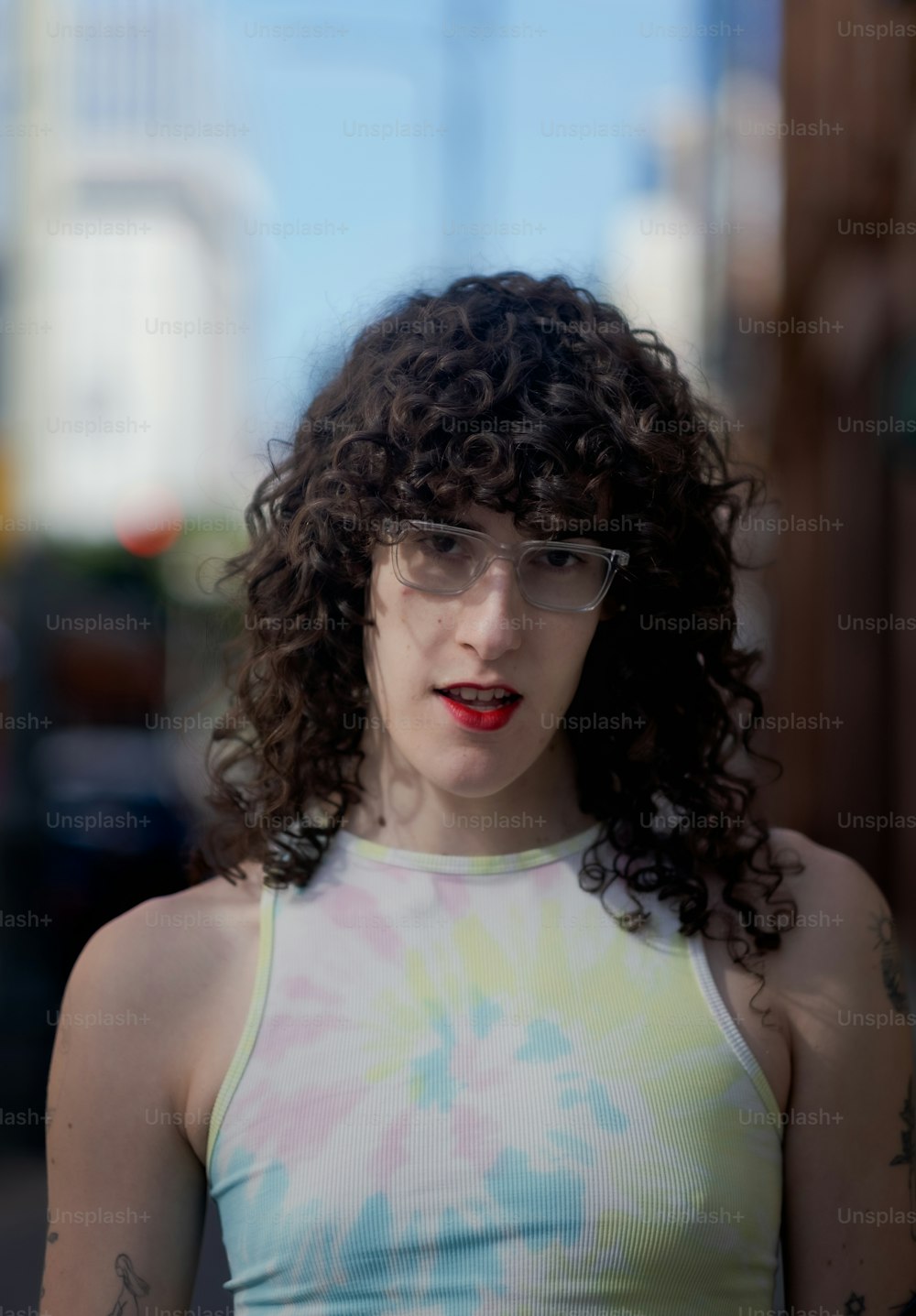 Una mujer con gafas y una camiseta sin mangas tie dye