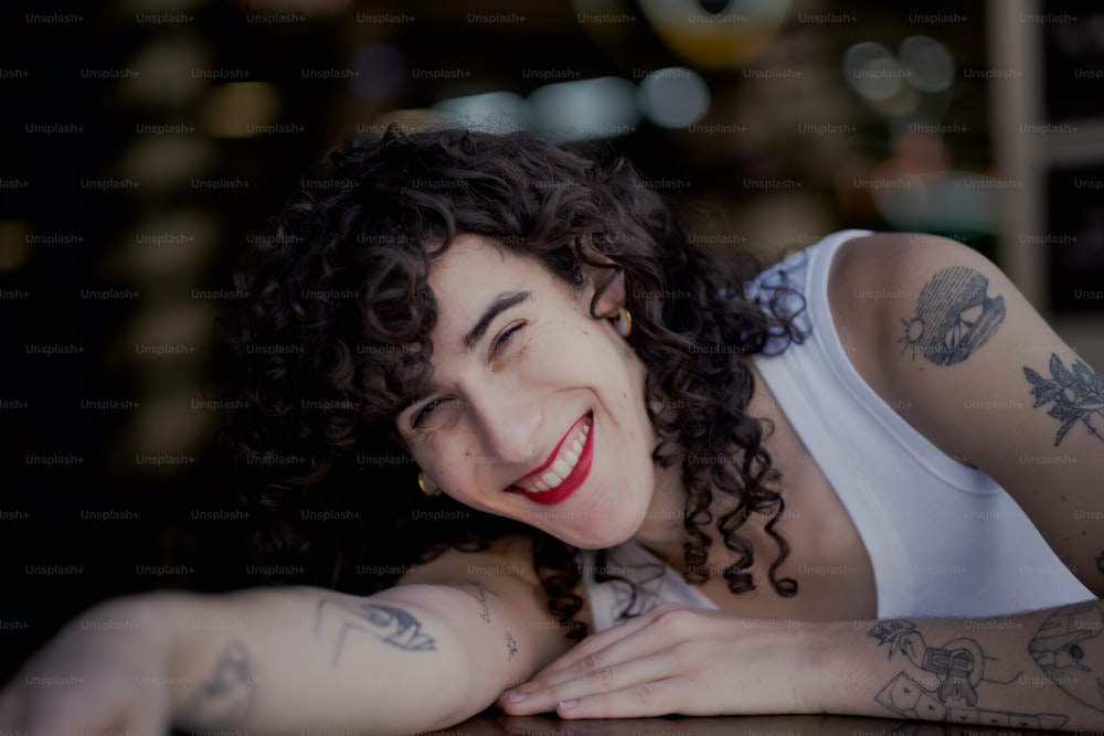 Une femme souriante avec des tatouages sur les bras