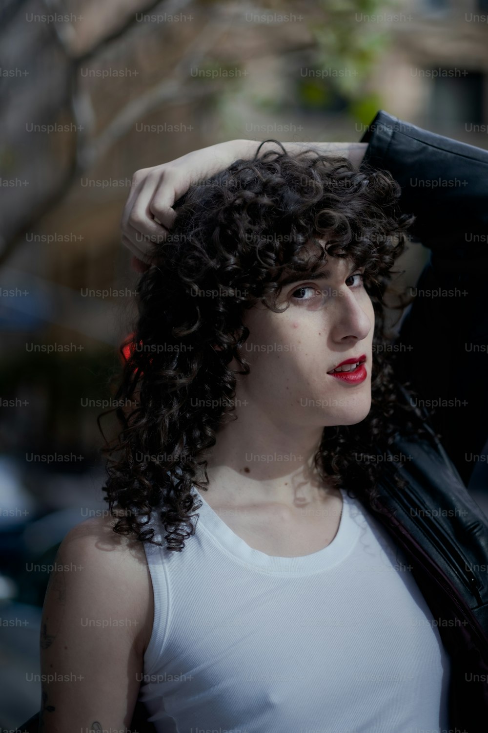a woman with curly hair and a white tank top