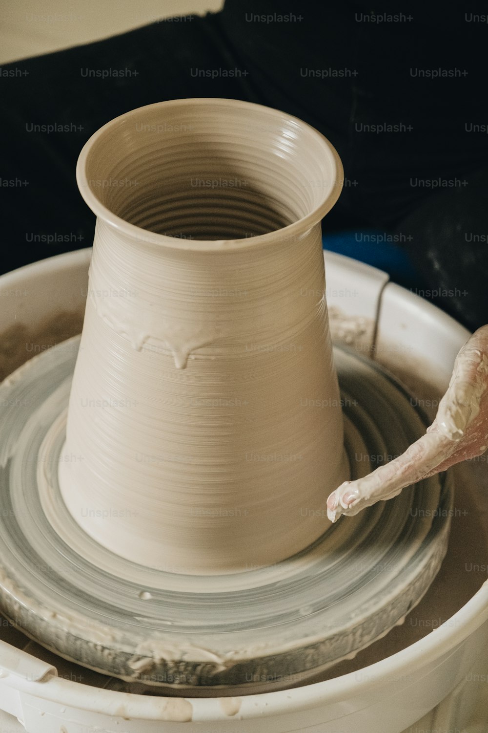 a person is making a vase on a potter's wheel