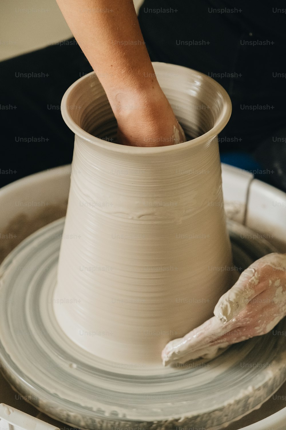 a person is making a vase on a potter's wheel