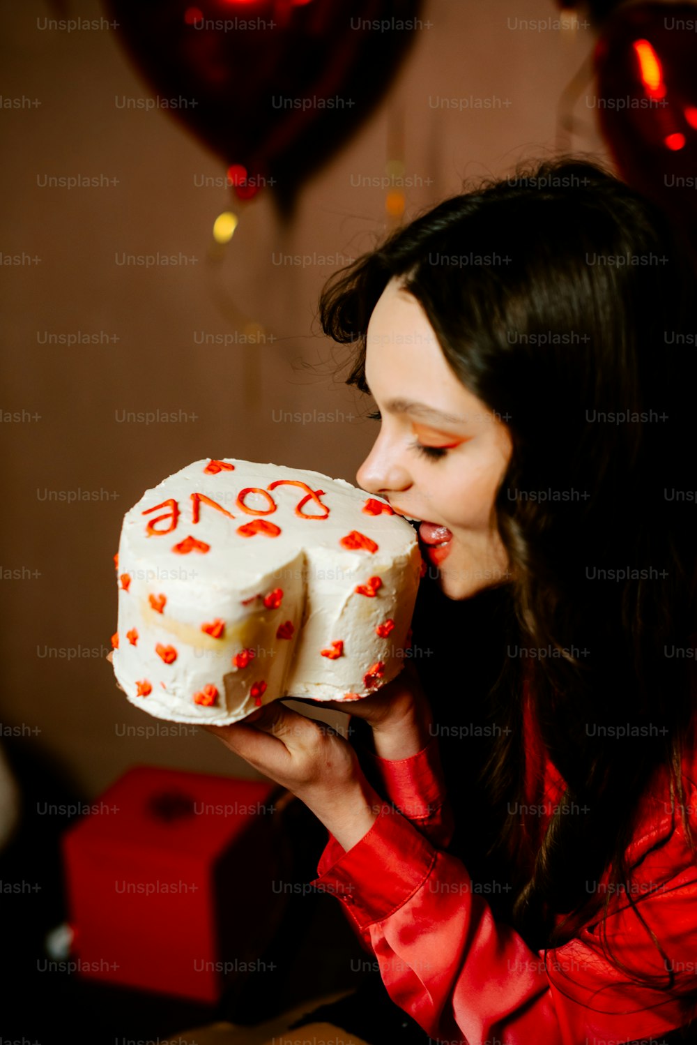 a woman biting into a cake with hearts on it