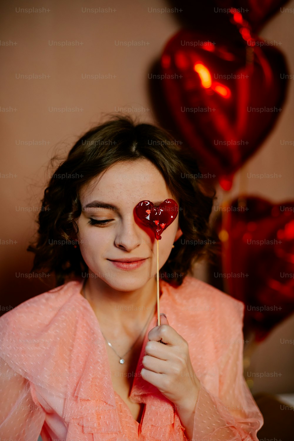 a woman holding a heart shaped lollipop in her hands