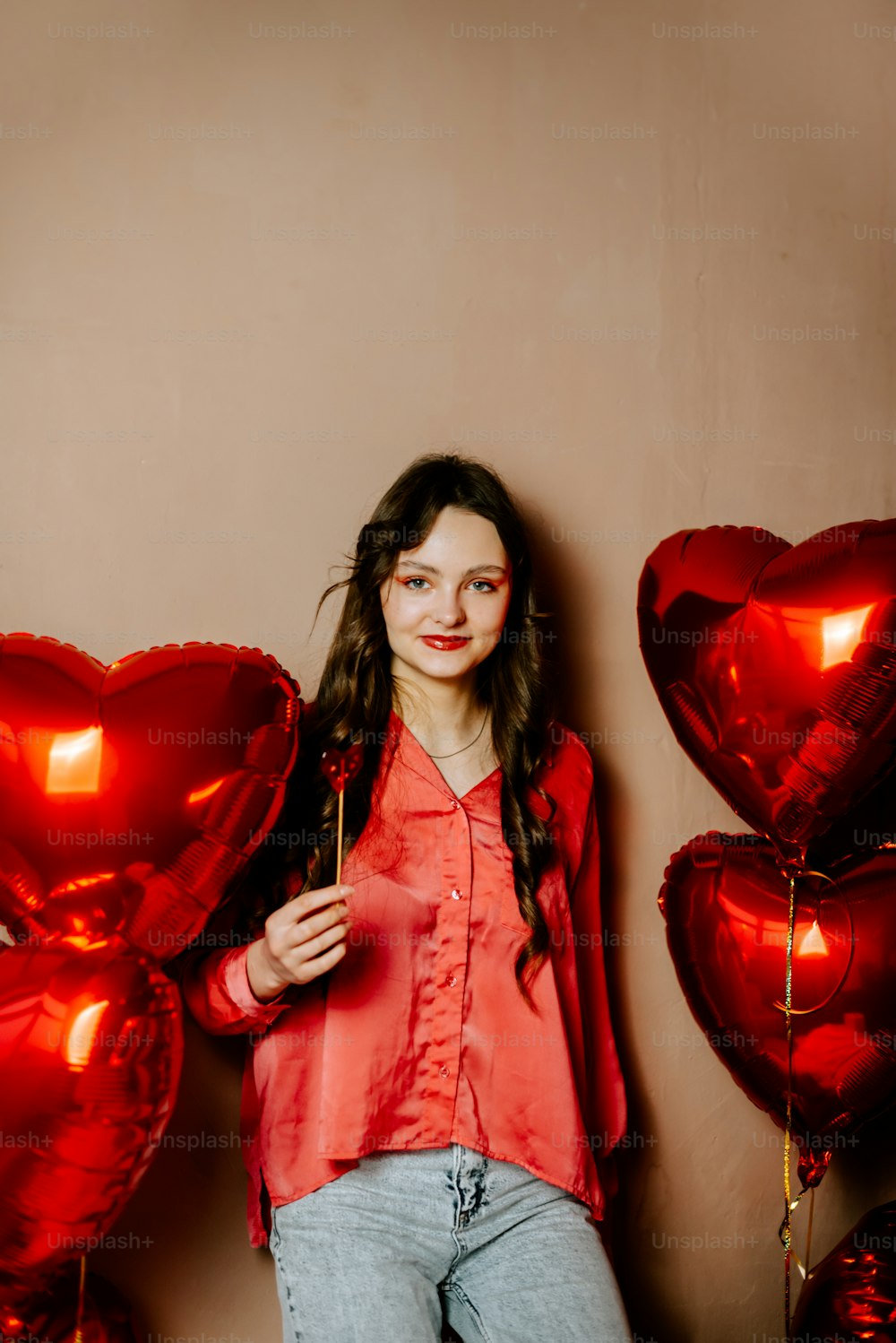a woman standing in front of red heart balloons