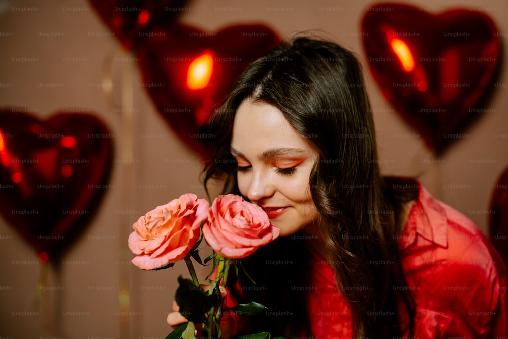 a woman smelling a rose in front of heart shaped balloons