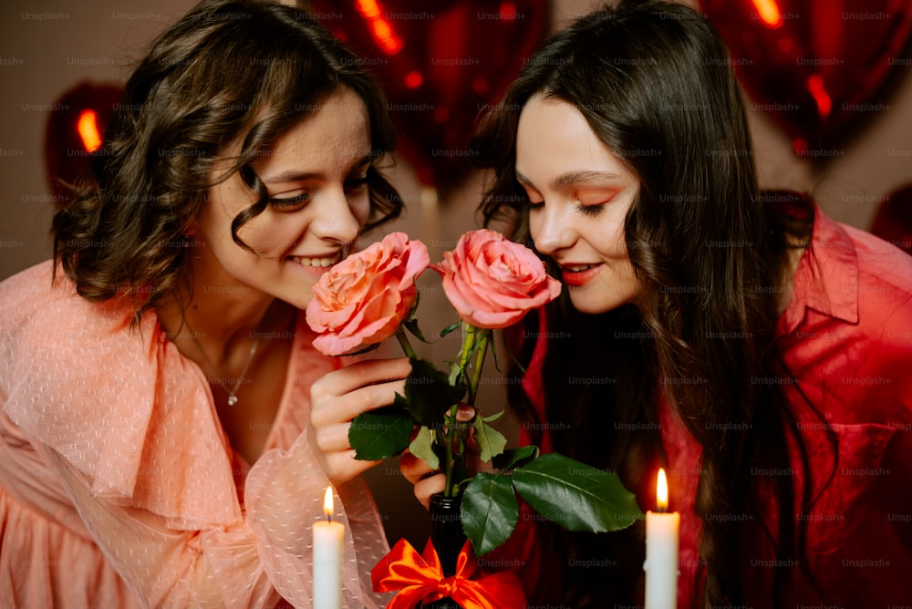 two women are looking at a rose on a table