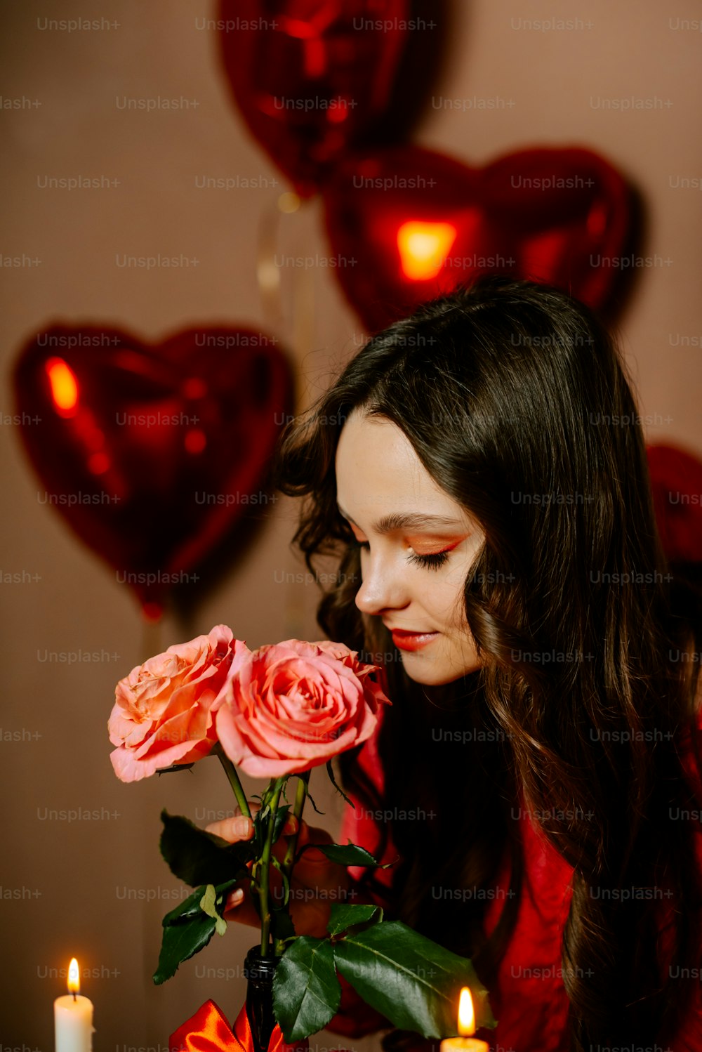 a woman smelling a bouquet of roses in front of candles