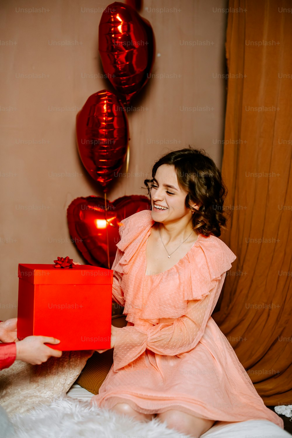 a woman in a pink dress holding a red box