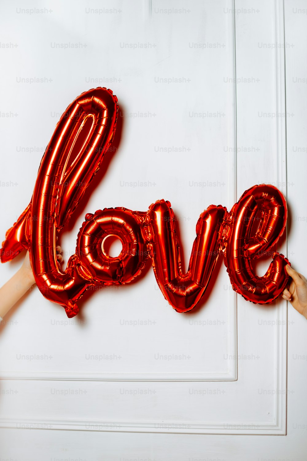 Eine Person, die einen roten Ballon in Form des Wortes Liebe hält