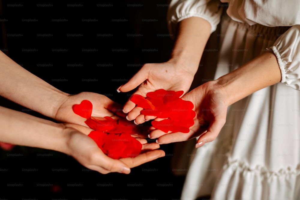 a group of people holding red hearts in their hands