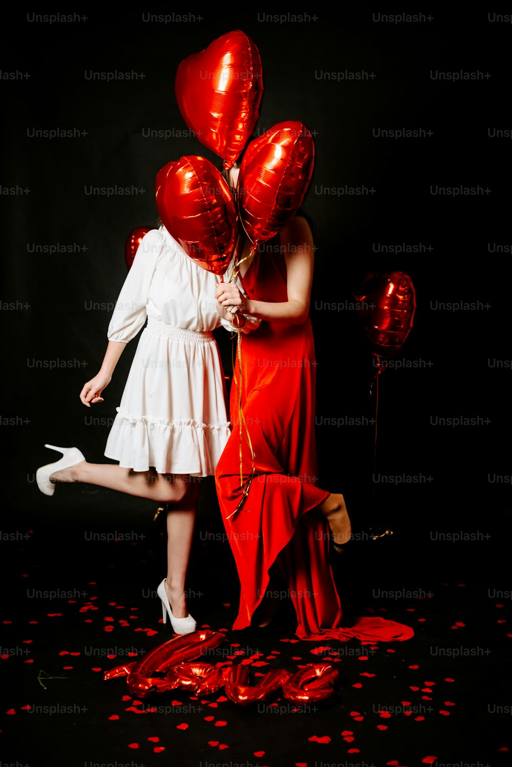 a couple of women standing next to each other holding red balloons