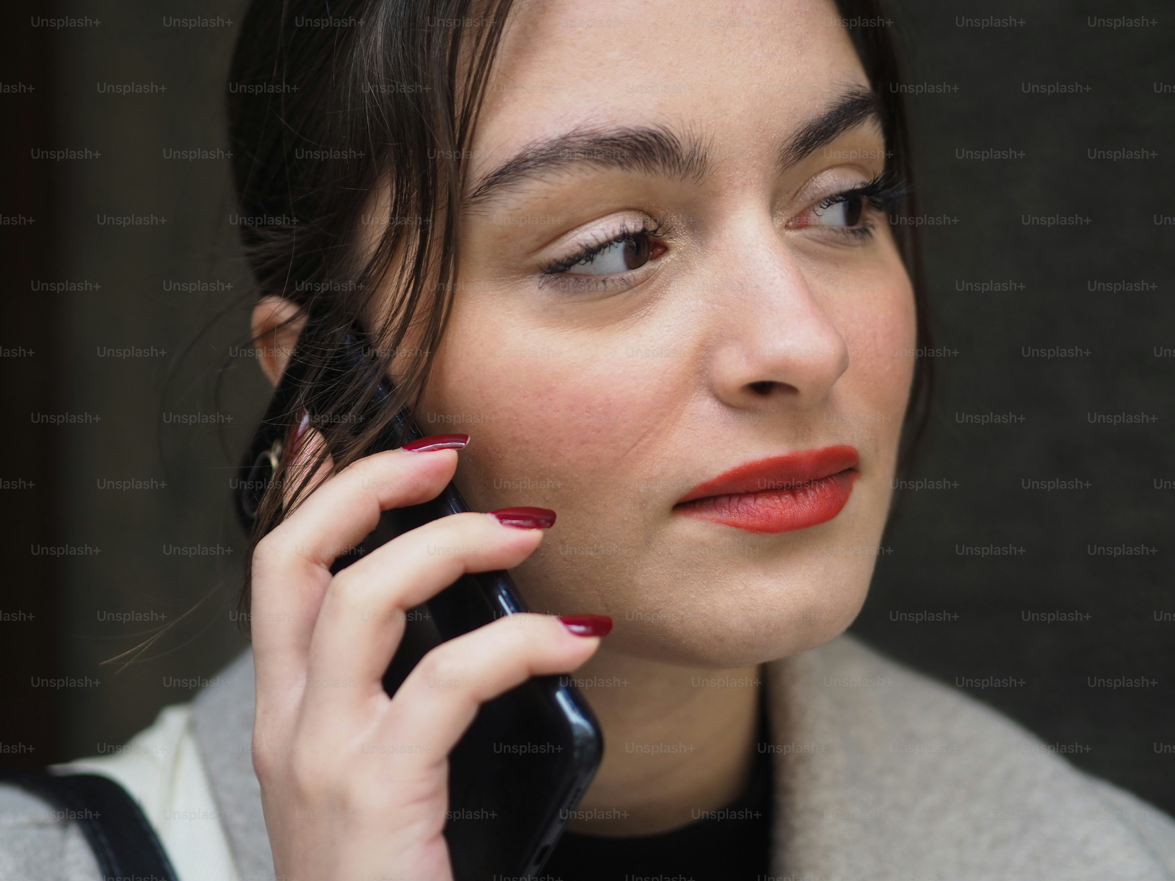 a woman talking on a cell phone while wearing red lipstick