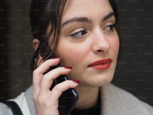 a woman talking on a cell phone while wearing red lipstick
