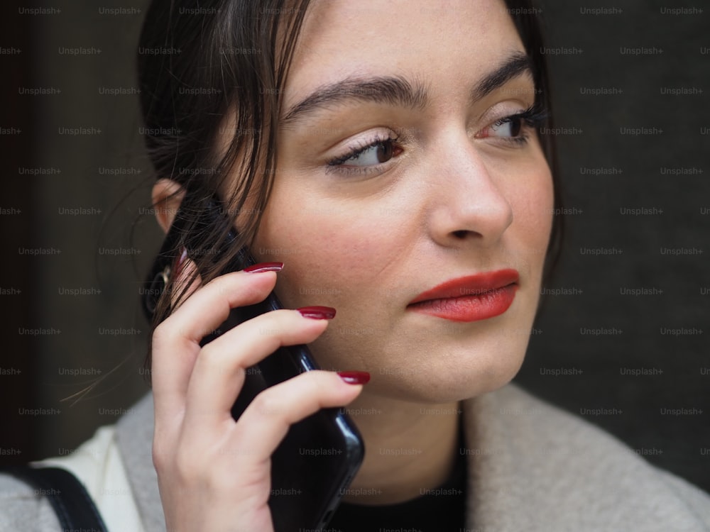 a woman talking on a cell phone while wearing red lipstick