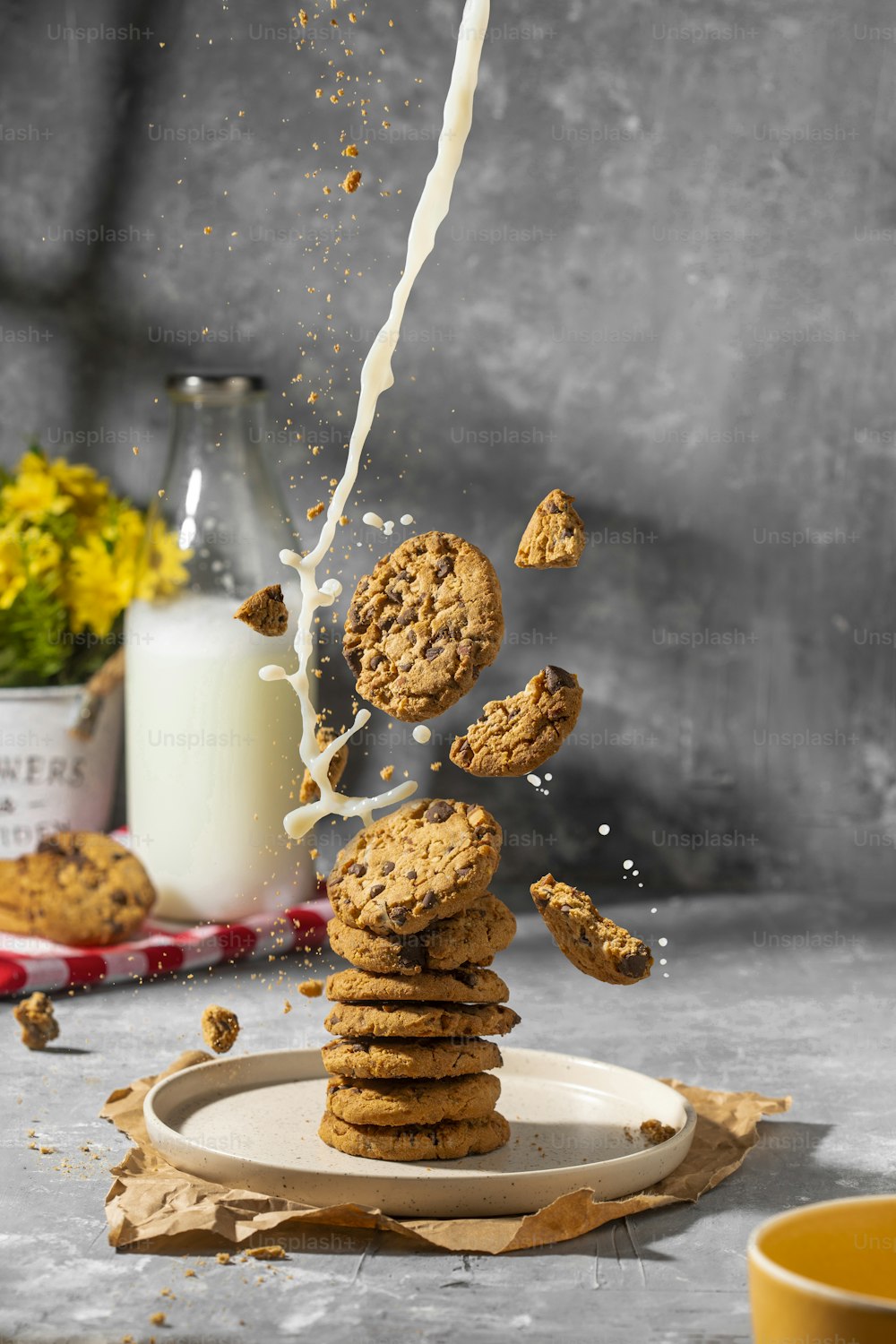 a stack of cookies falling into a glass of milk