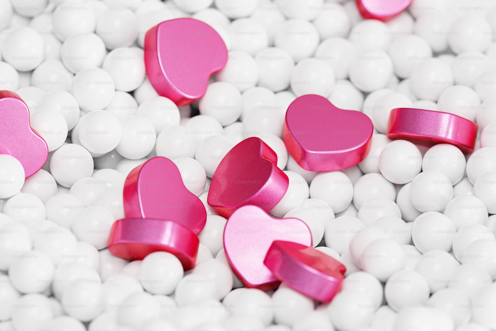 un tas de boules blanches avec des cœurs roses dessus