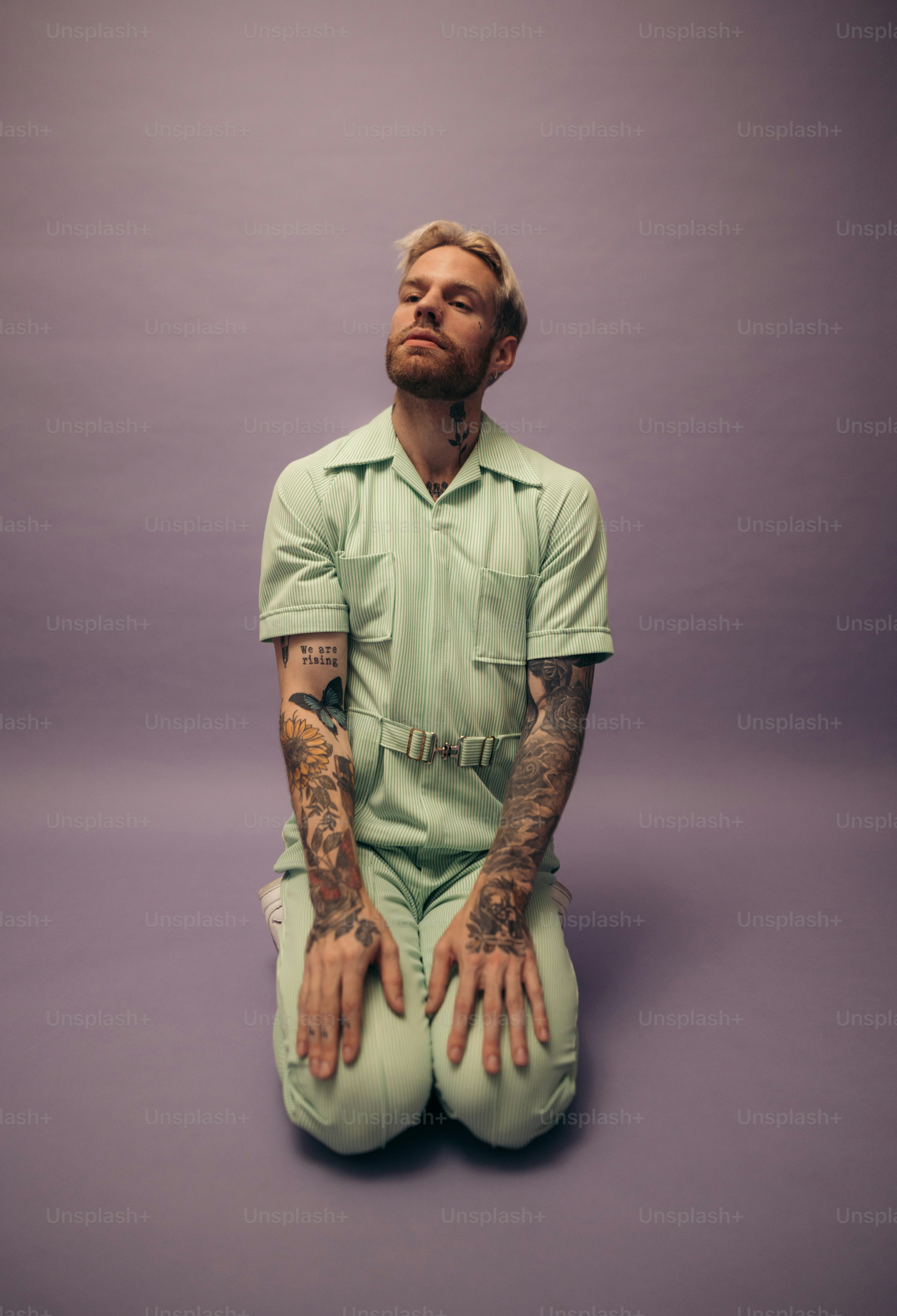 a man with tattoos sitting on the ground