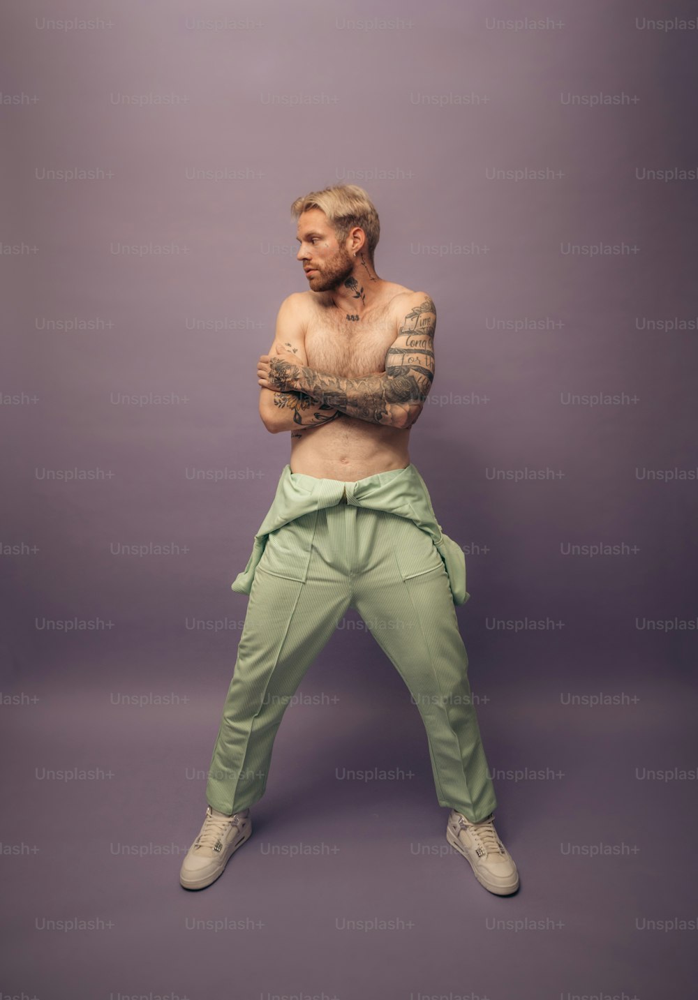 a man with a tattooed arm standing in front of a purple background
