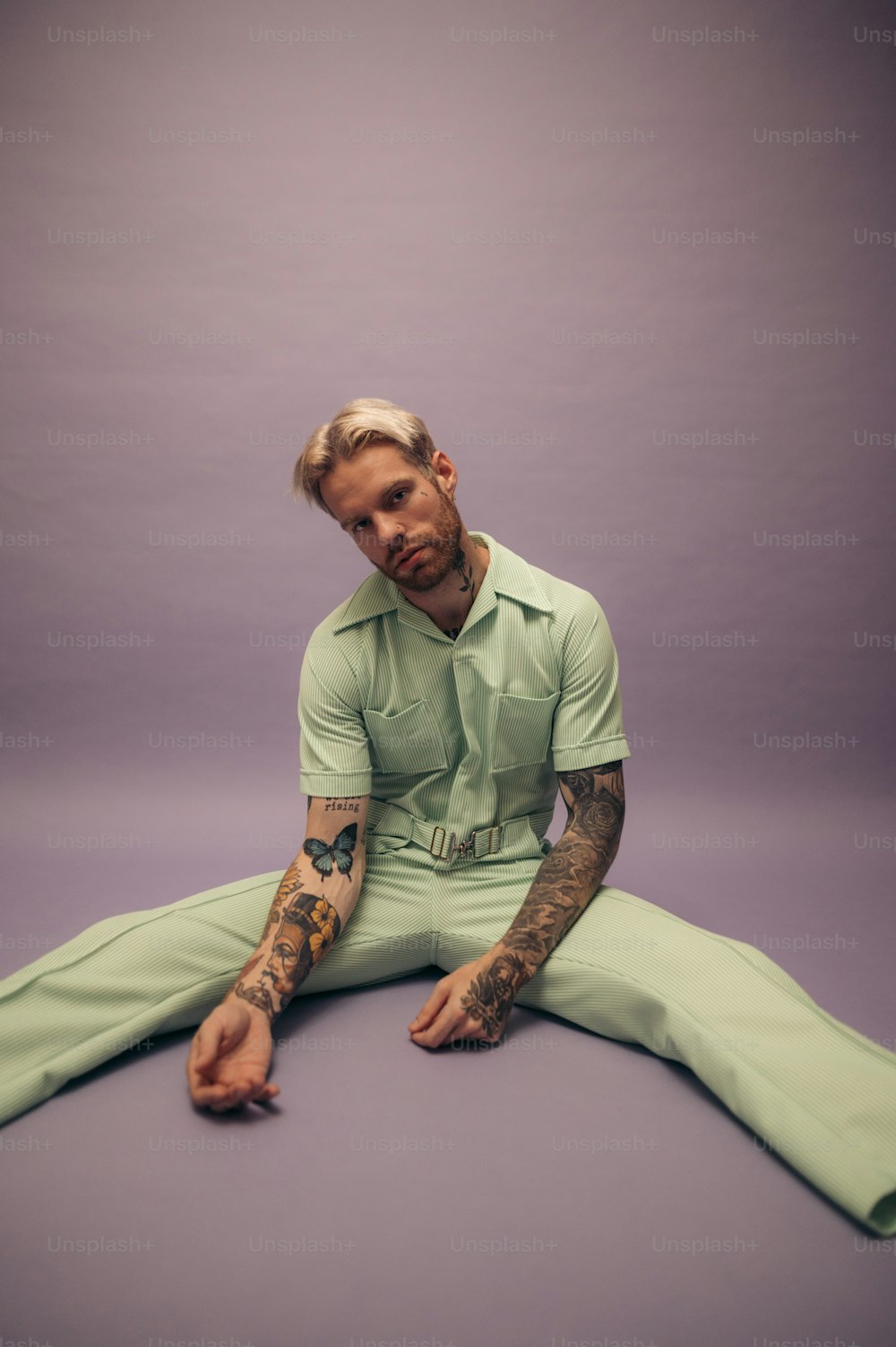 a man with tattoos sitting on the ground