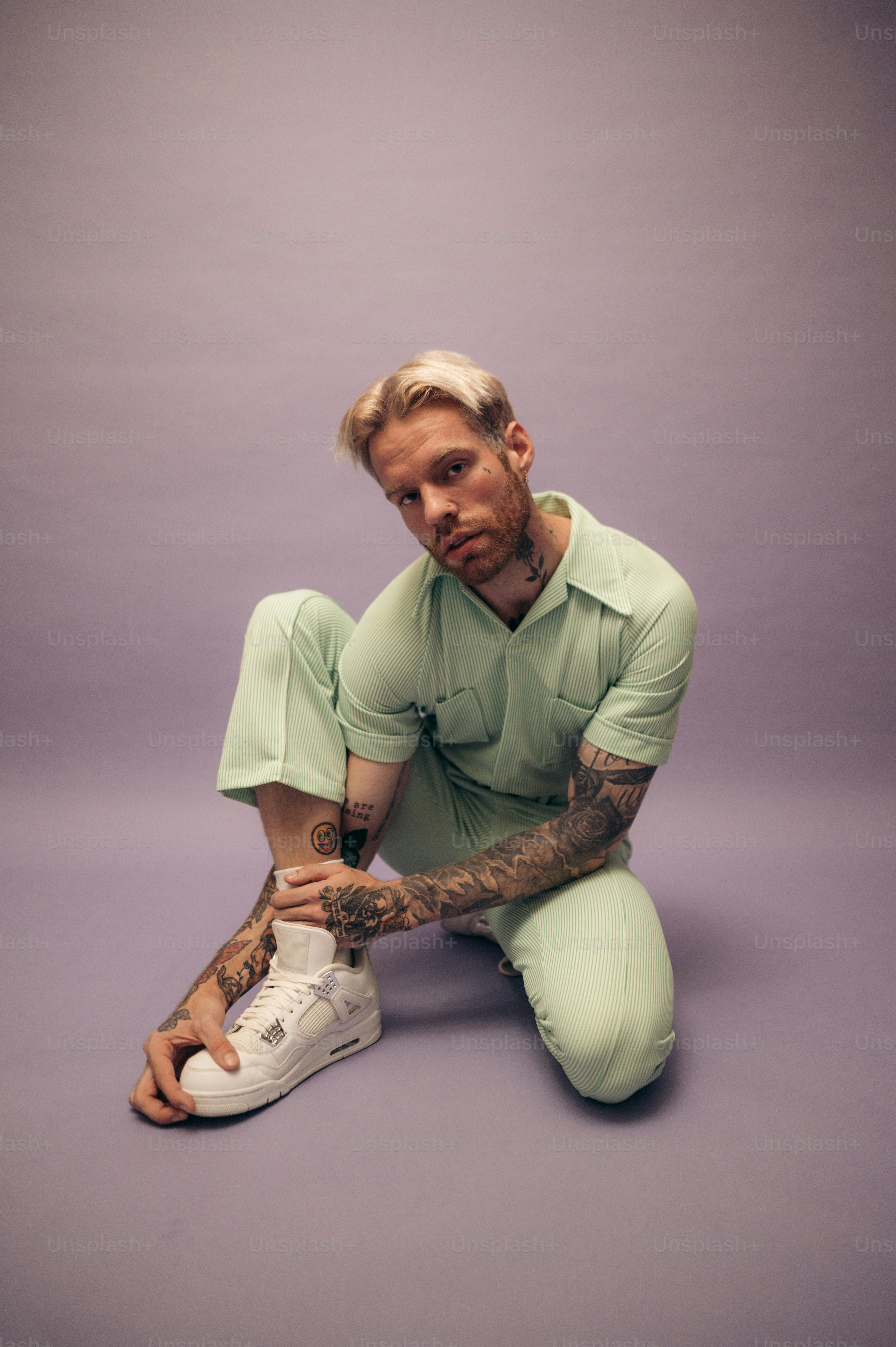 a man with tattoos sitting on the ground