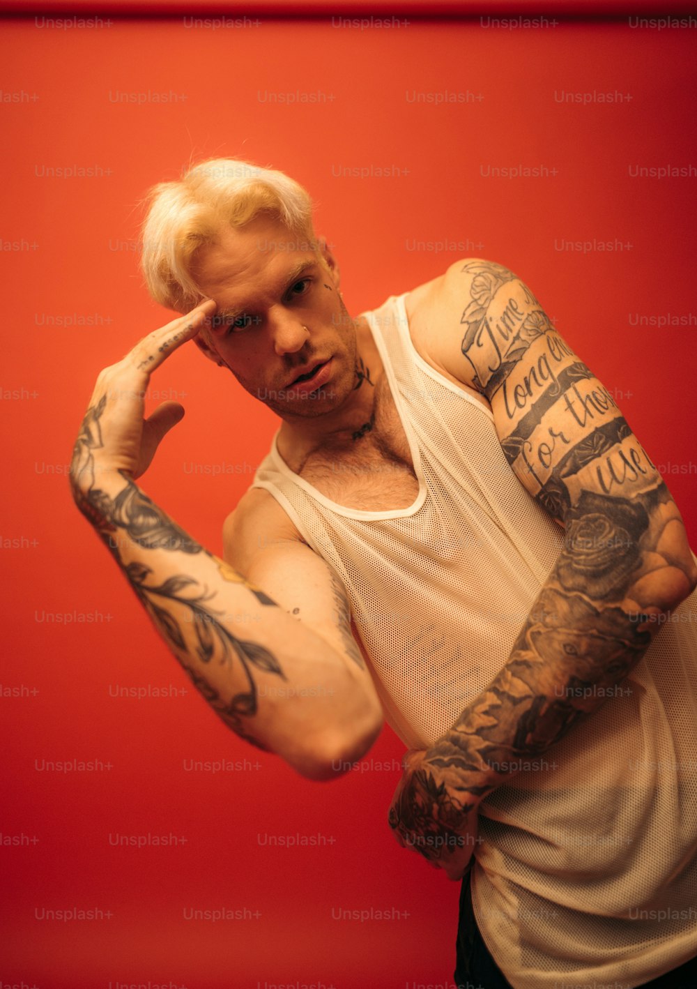 Un hombre con el pelo blanco y tatuajes en los brazos
