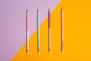 three pencils lined up on a yellow and purple background