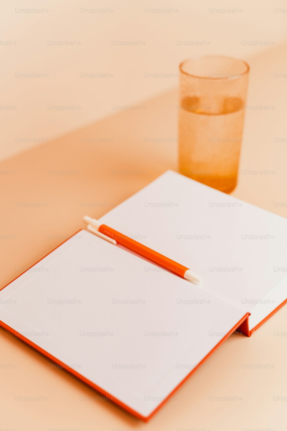 a notepad with a pen on top of it next to a glass