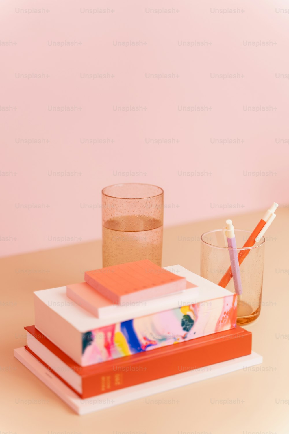 a stack of books sitting next to a glass of water