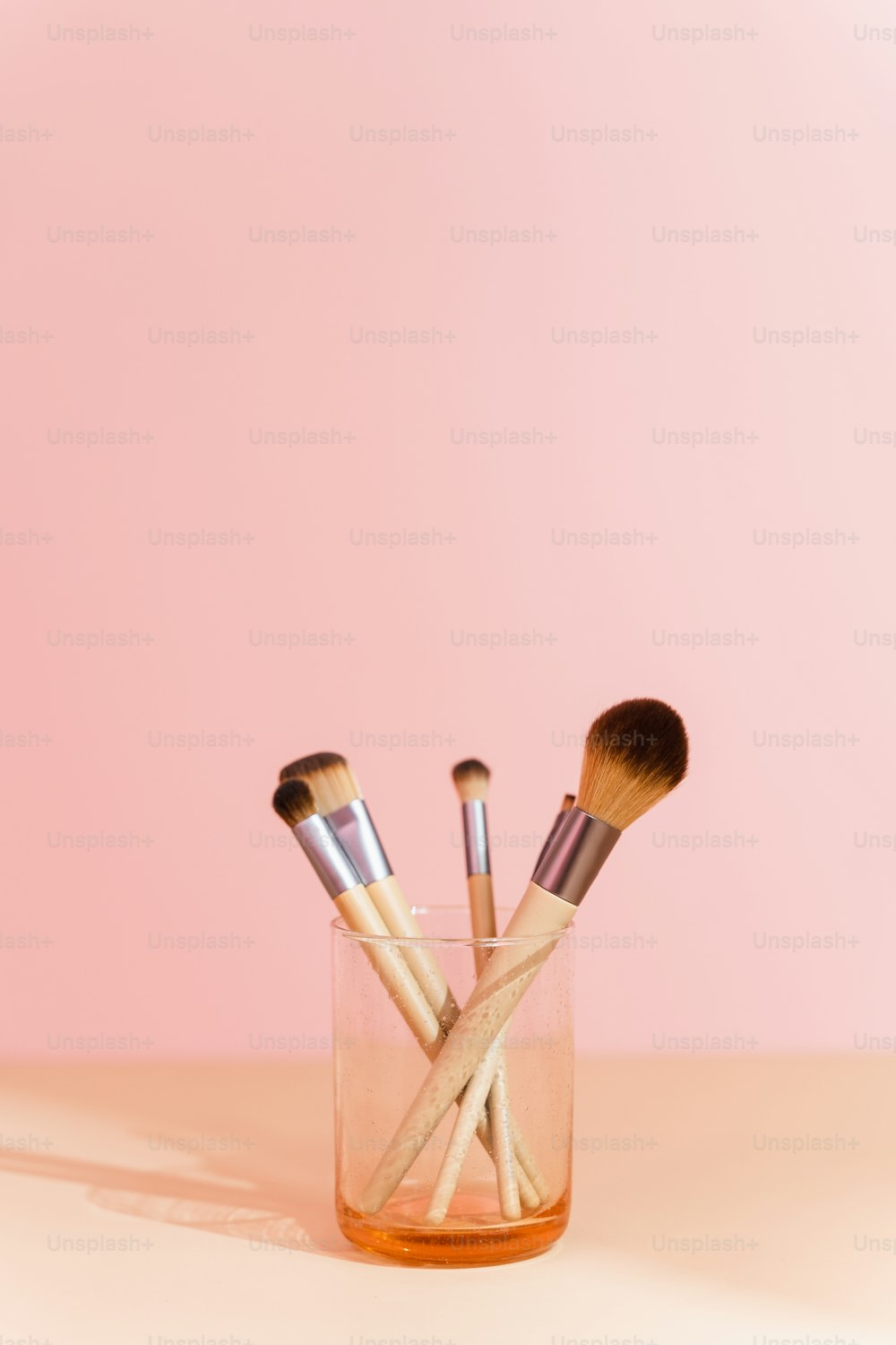 a glass filled with makeup brushes on top of a table