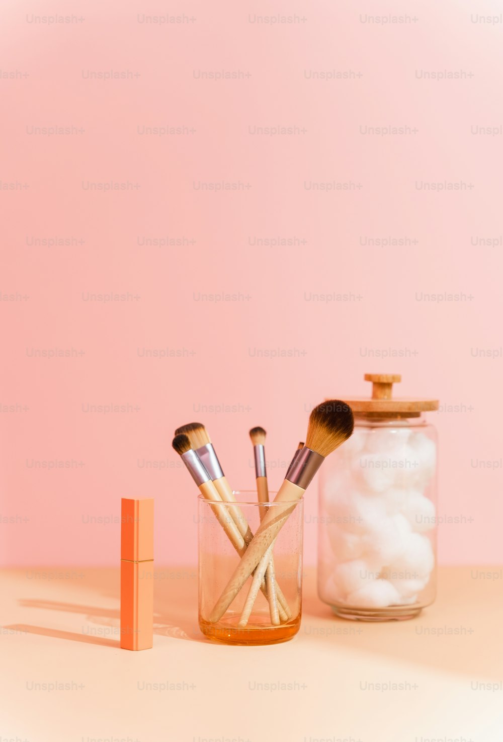 a jar filled with makeup brushes next to a container of cotton