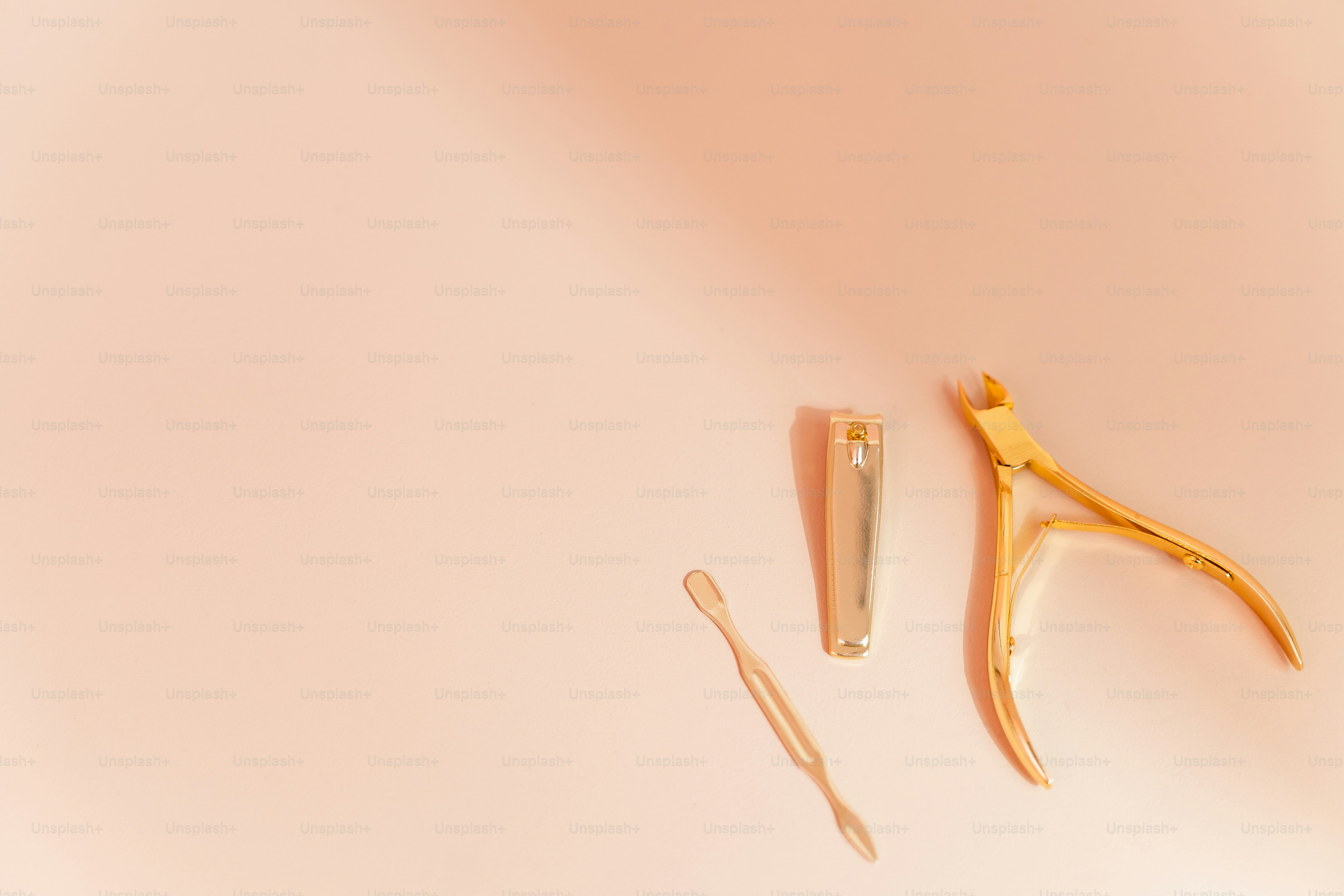 a pair of scissors and a comb on a pink surface