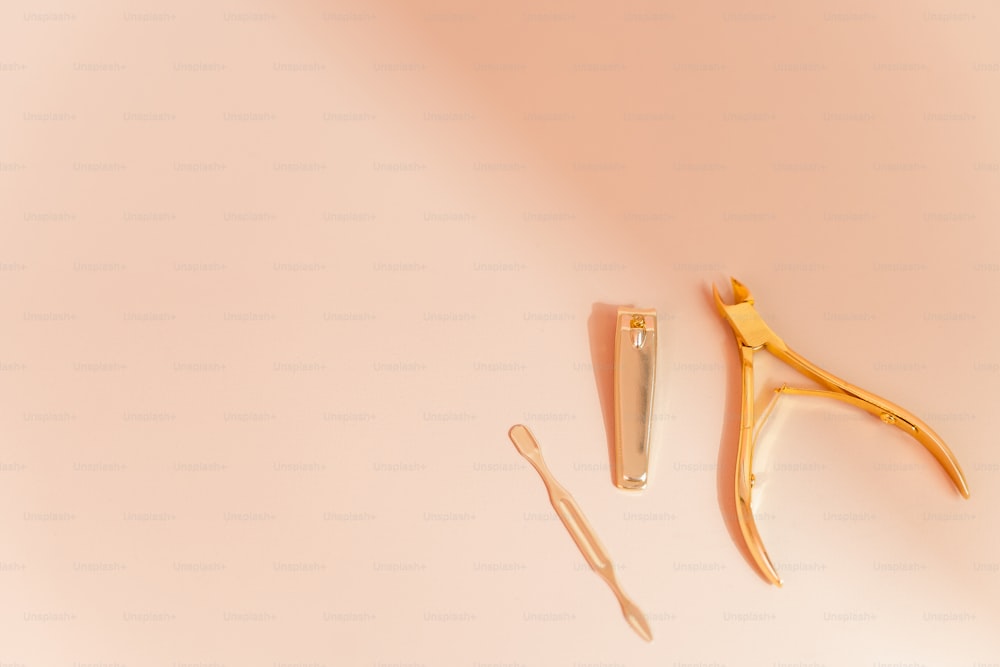 a pair of scissors and a comb on a pink surface