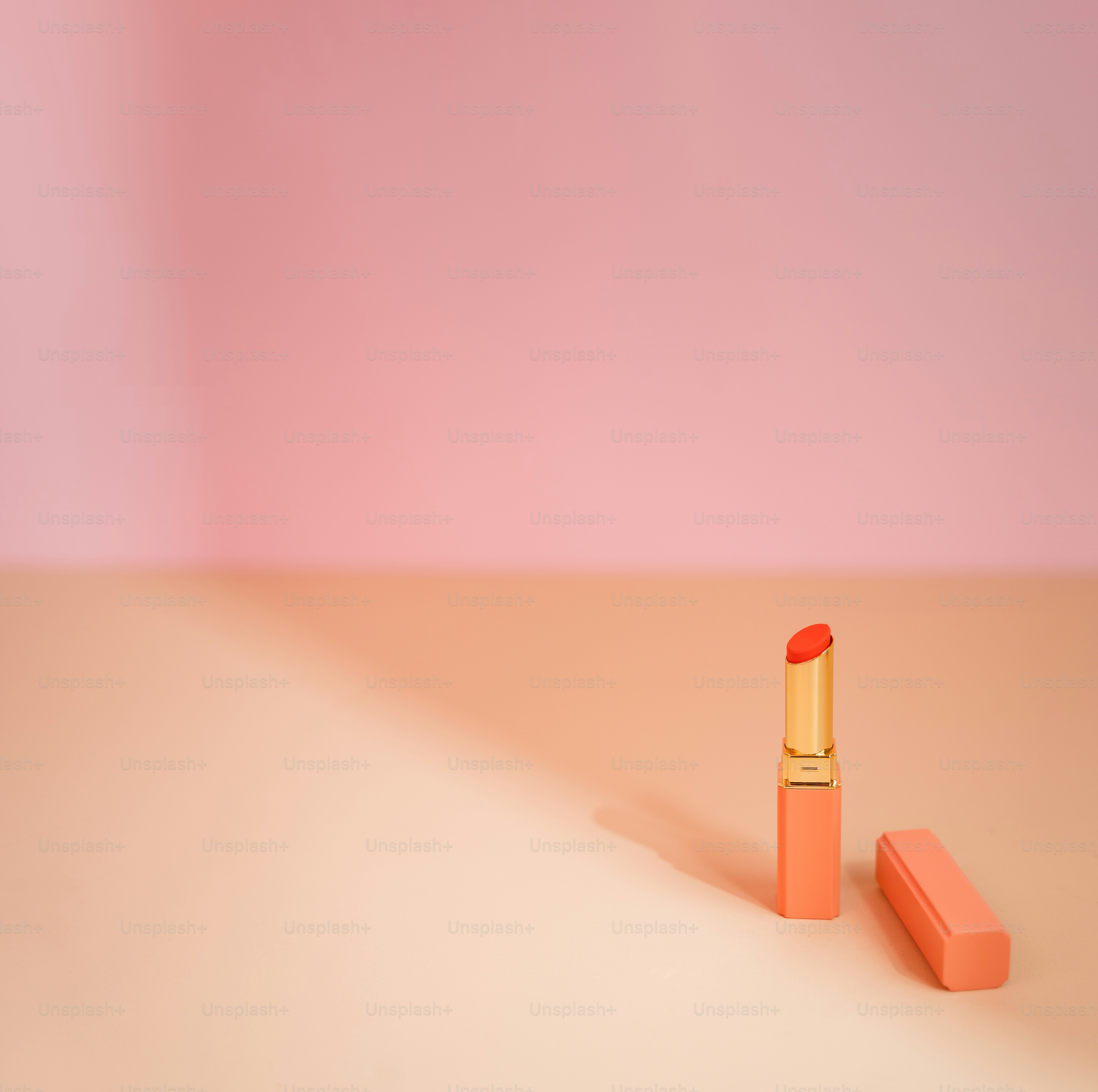 lipstik oranye dengan latar belakang merah muda