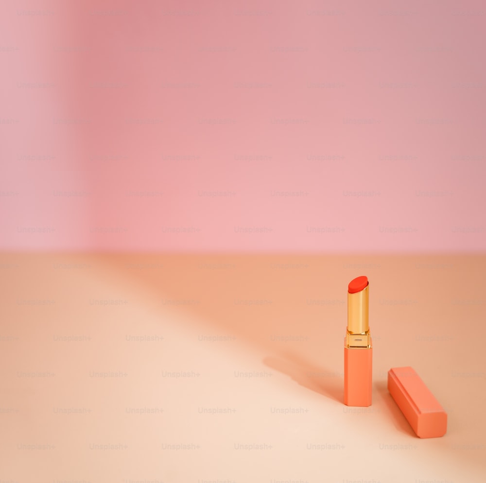 un lápiz labial naranja con un fondo rosa