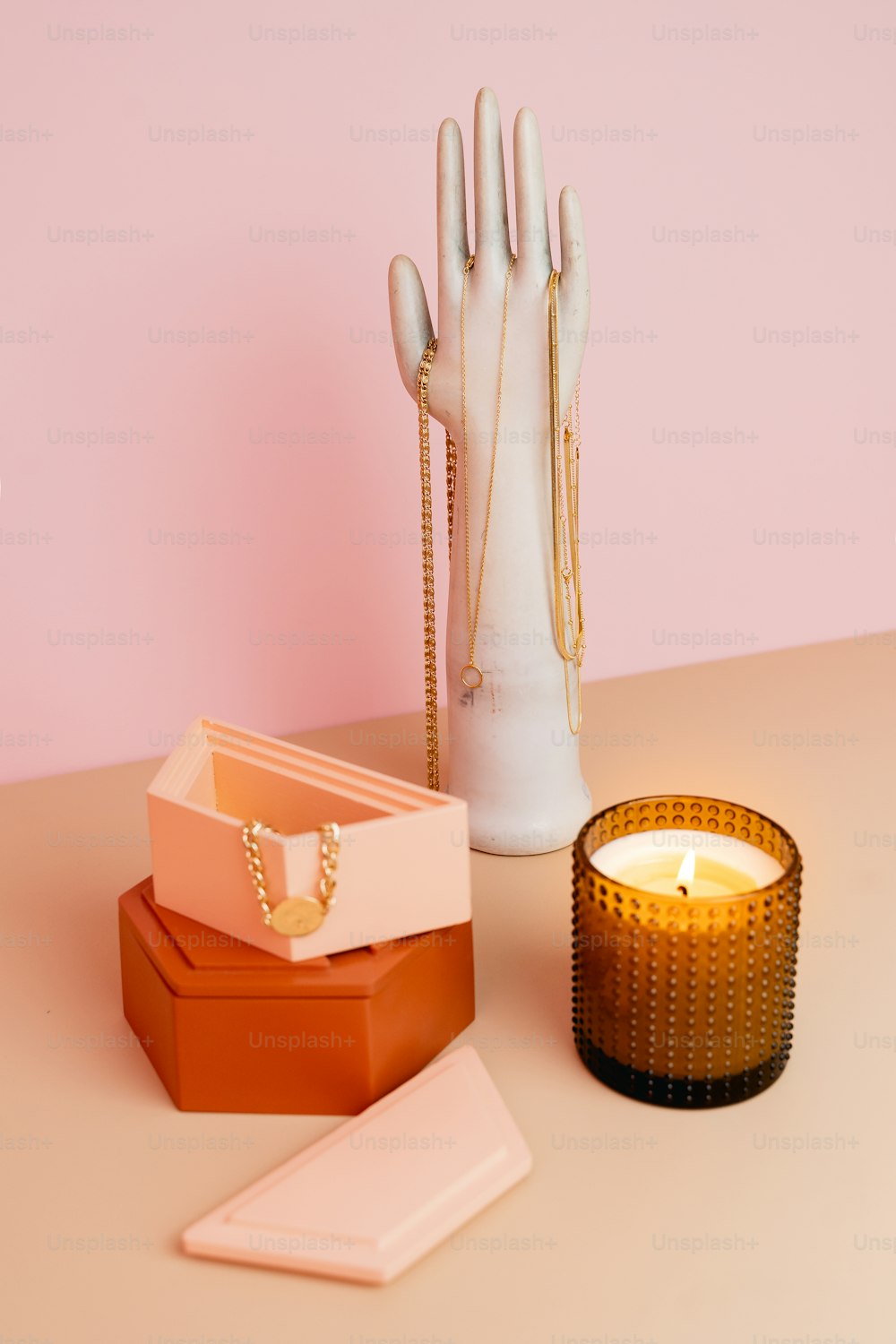 a table with a candle, ring box, and hand on it