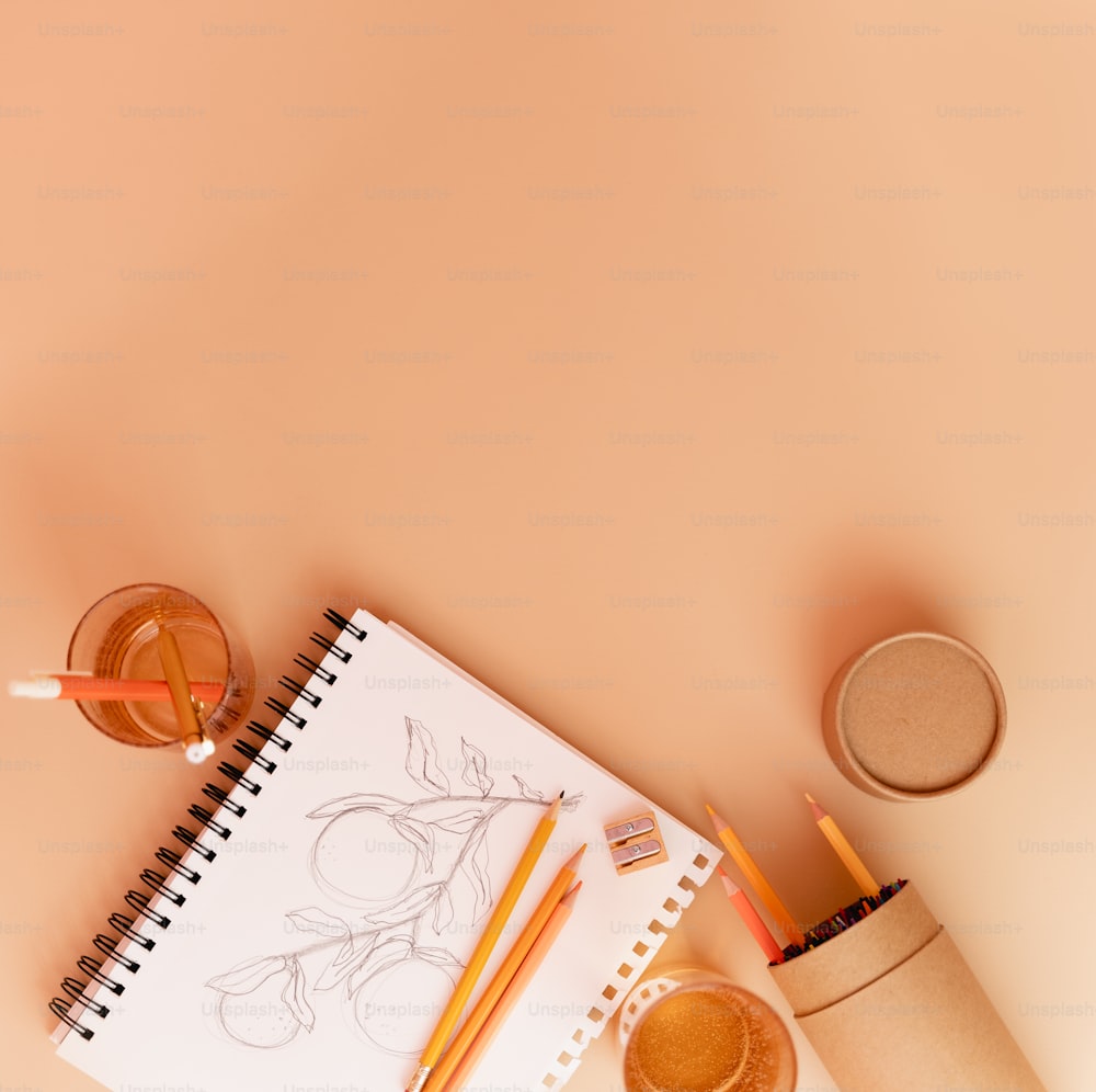 a notebook, pencils, and a cup of coffee on a table