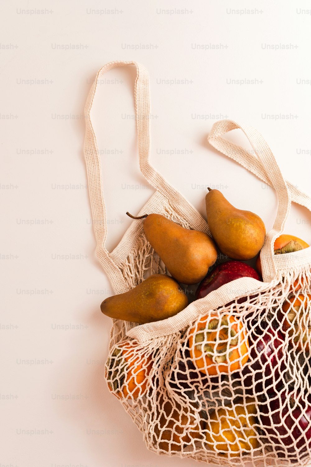 una borsa a rete piena di pere e arance