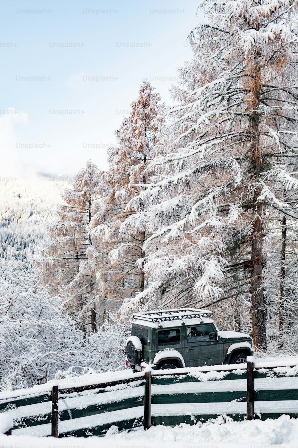 Un jeep está estacionado en la nieve cerca de una cerca