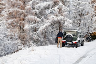 a man standing next to a jeep in the snow