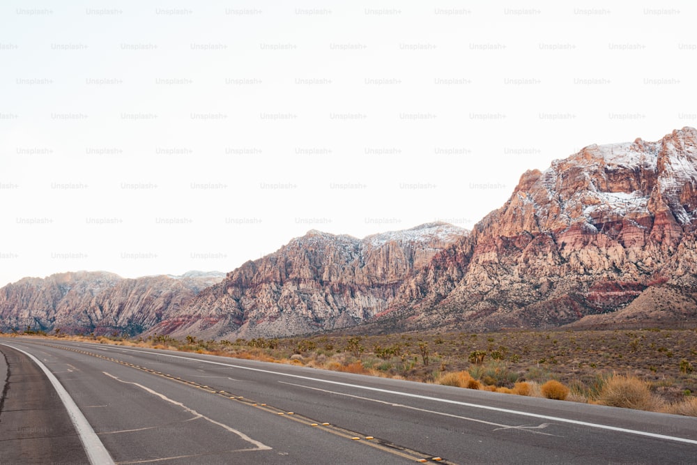 an empty highway with mountains in the background