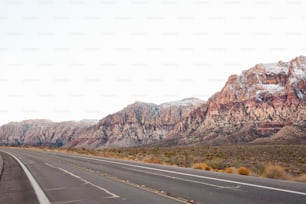 an empty highway with mountains in the background
