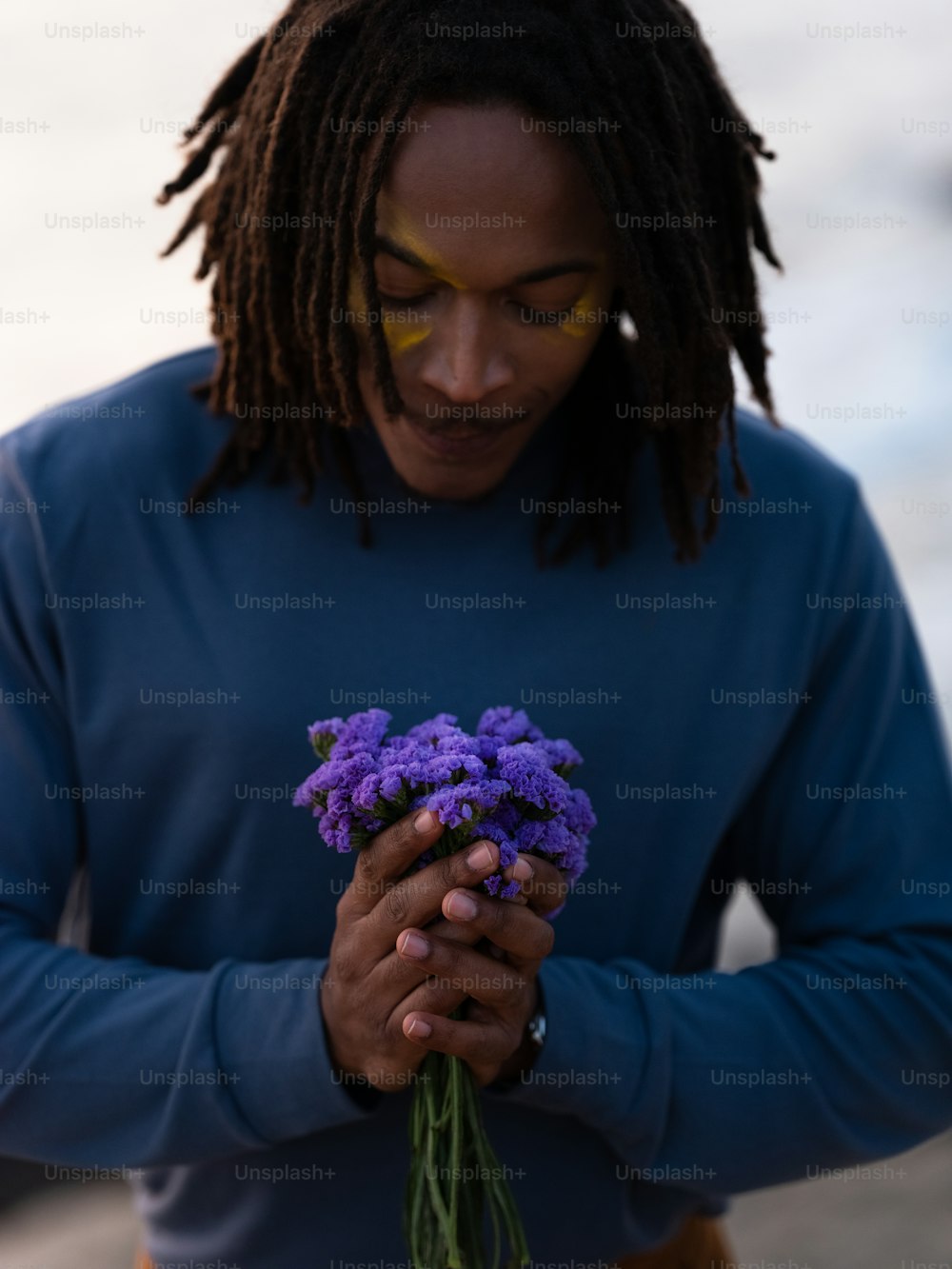 a man holding a bunch of purple flowers