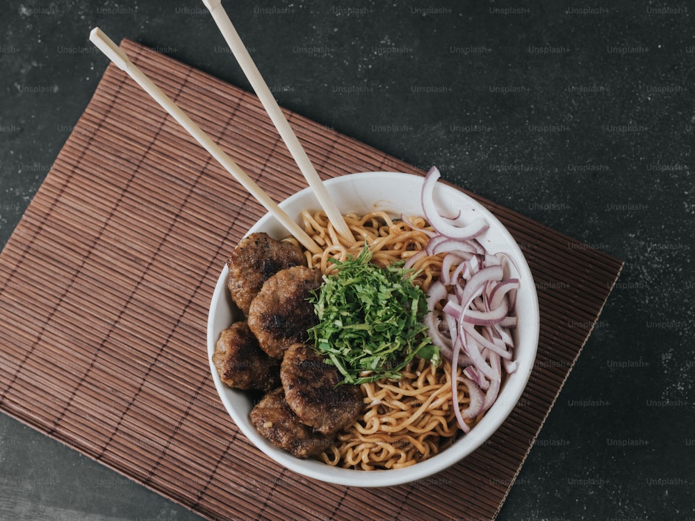 a bowl of noodles with meatballs and onions